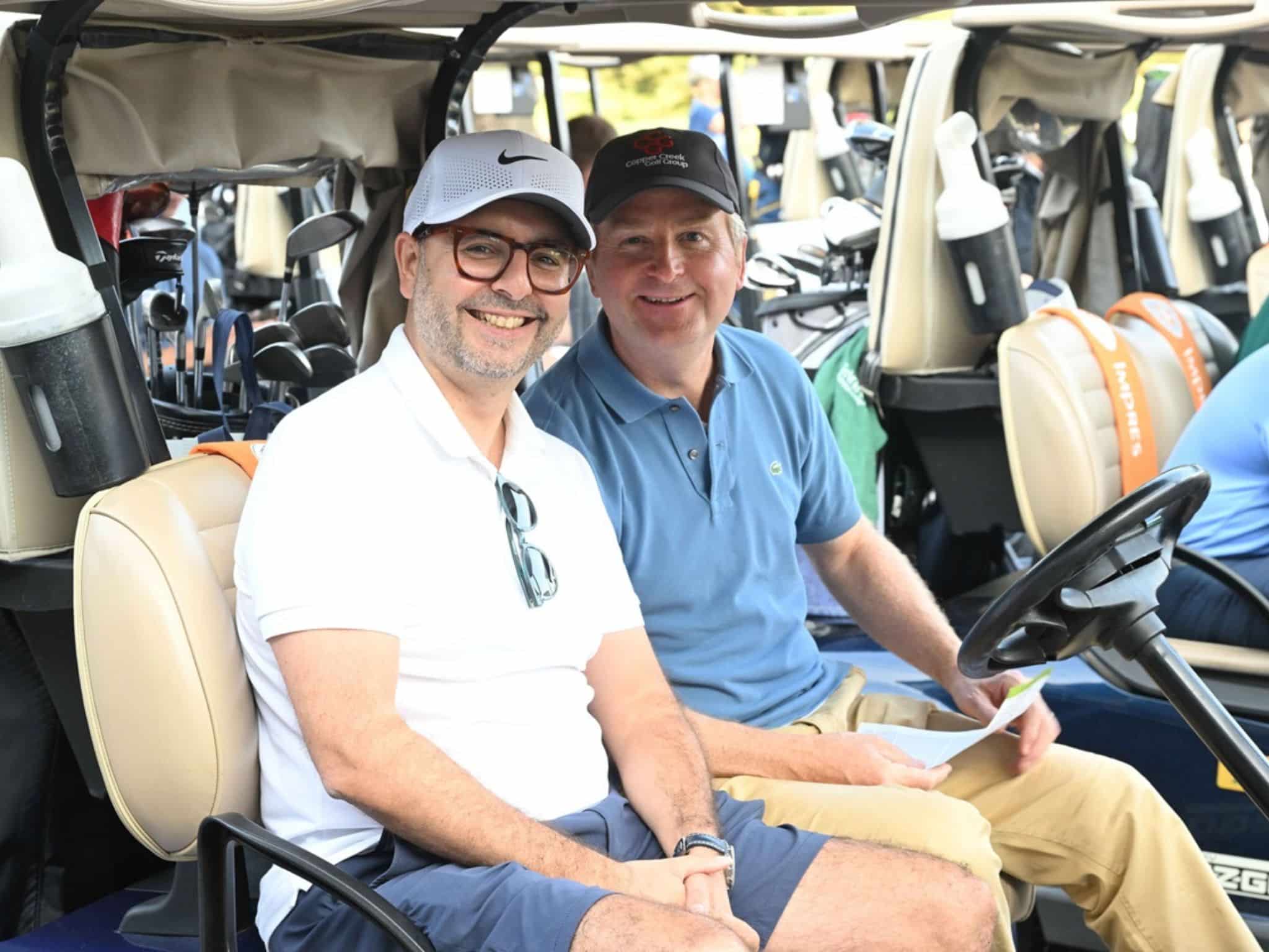 Two men smiling in golf cart