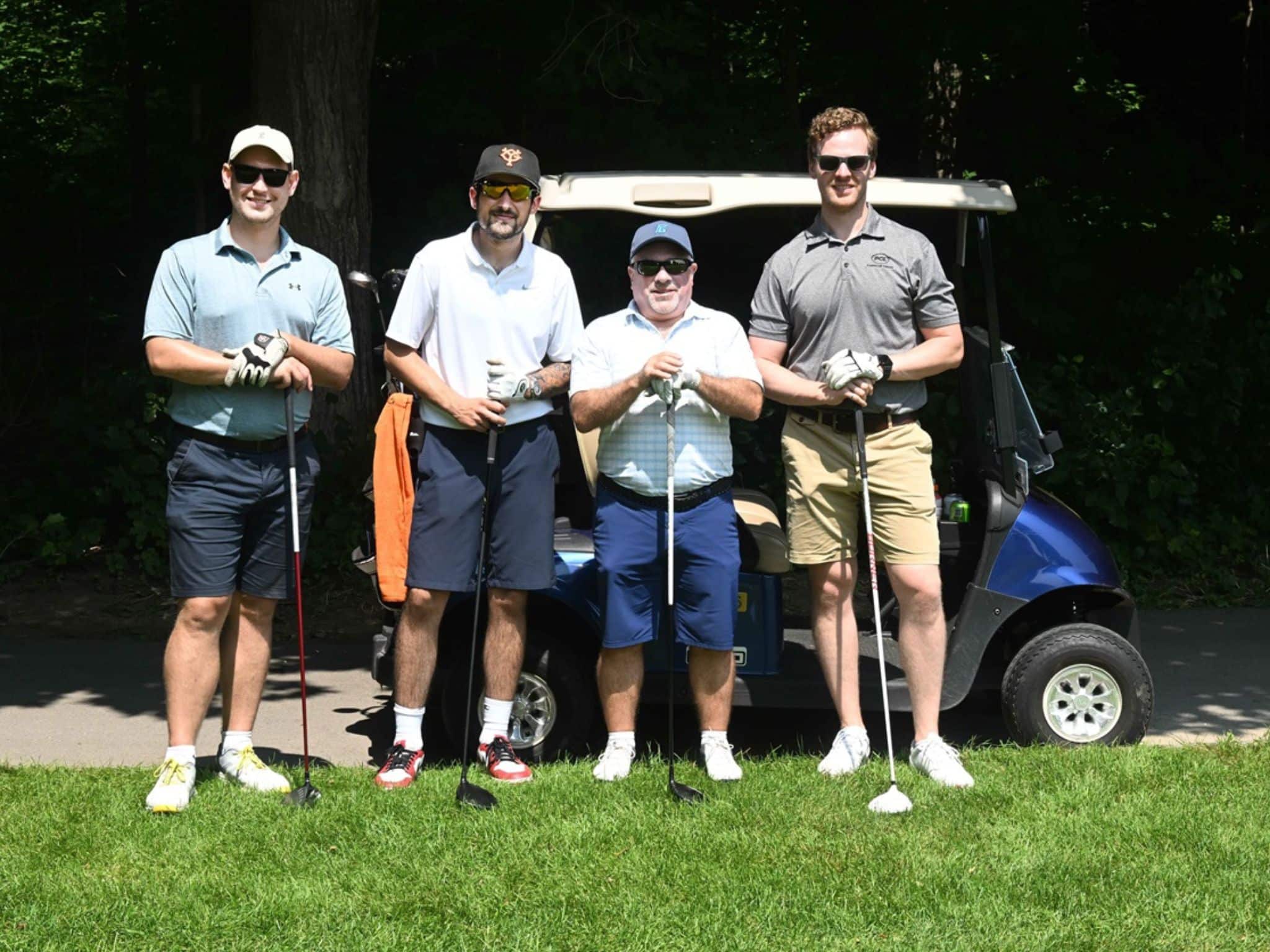 Four men posing with golf clubs