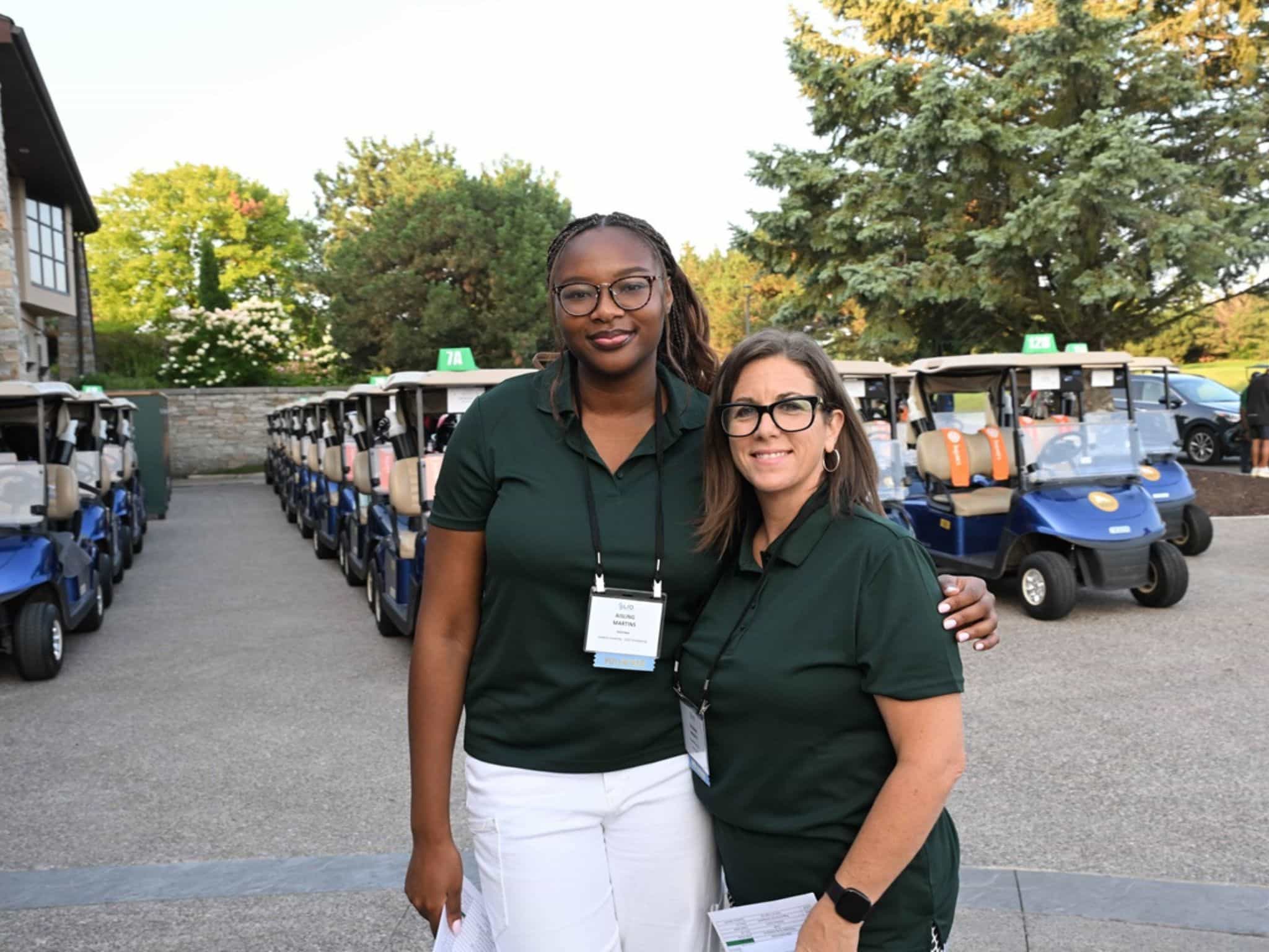 Two women smiling near golf carts