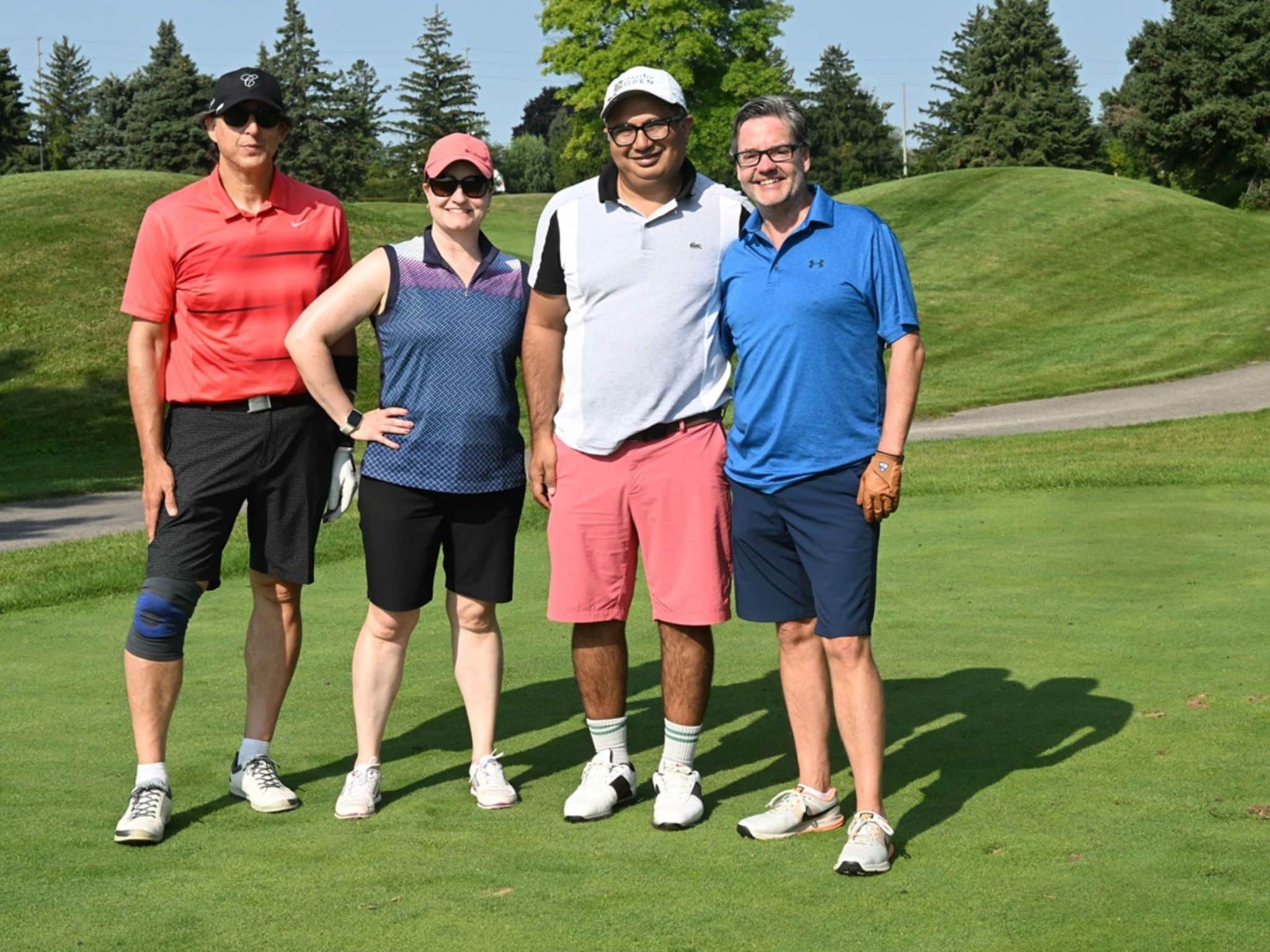 Four people posing on golf course