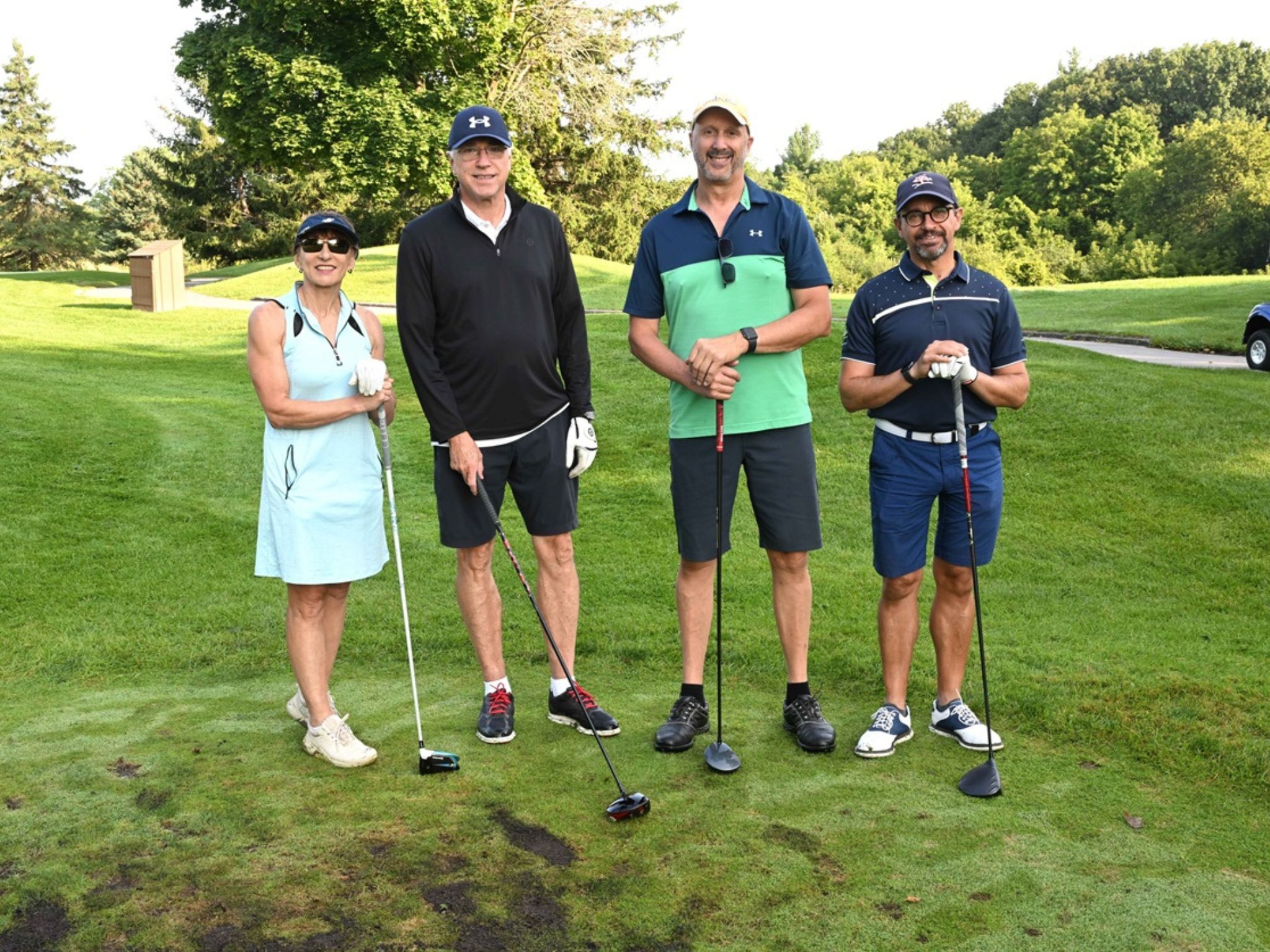 Four people posing on golf course